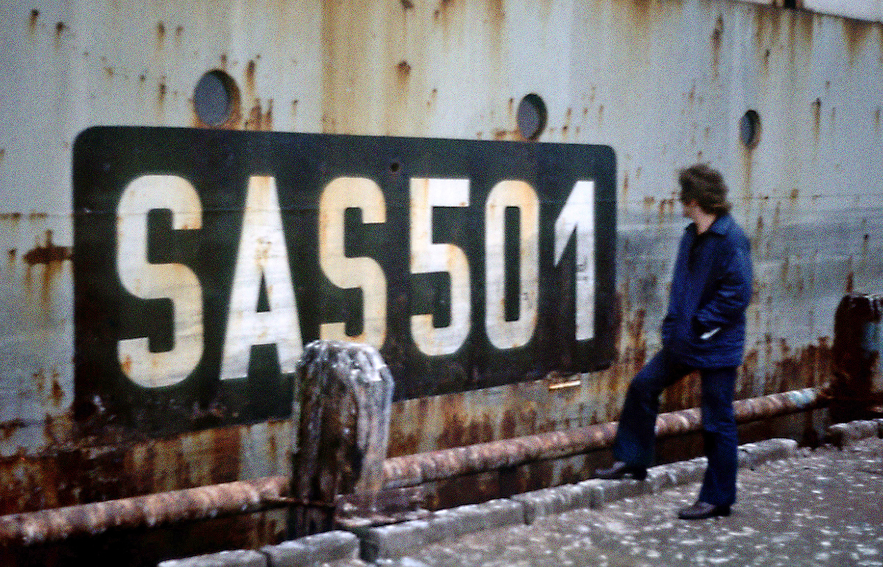 Schiffskennung "SAS 501" auf der Außenseite des Schiffes. Ein Mann steht davor.