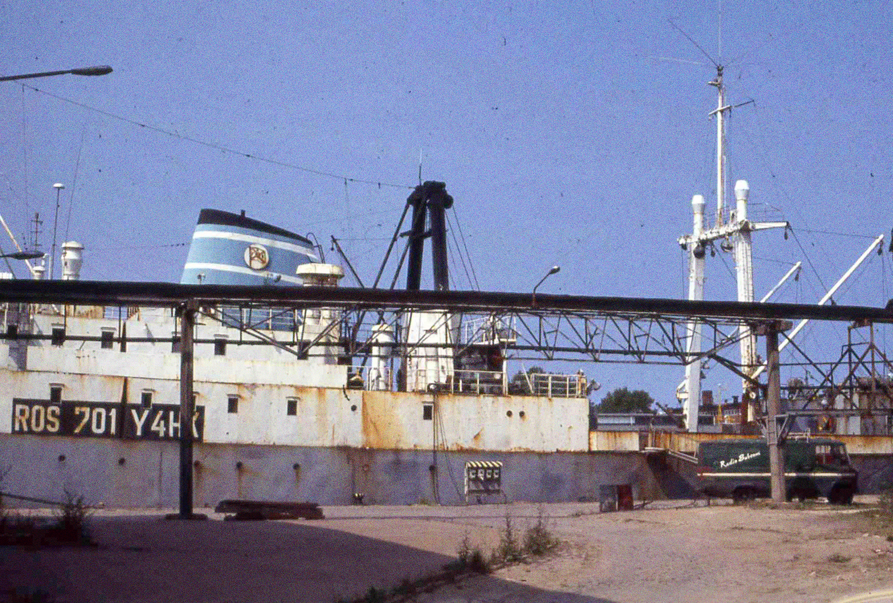 Die Stubnitz liegt an der Kaikante im Rostocker Hafen. Vor dem Schiff steht ein Fahrzeug mit der Aufschrift “Radio Subcom”.
