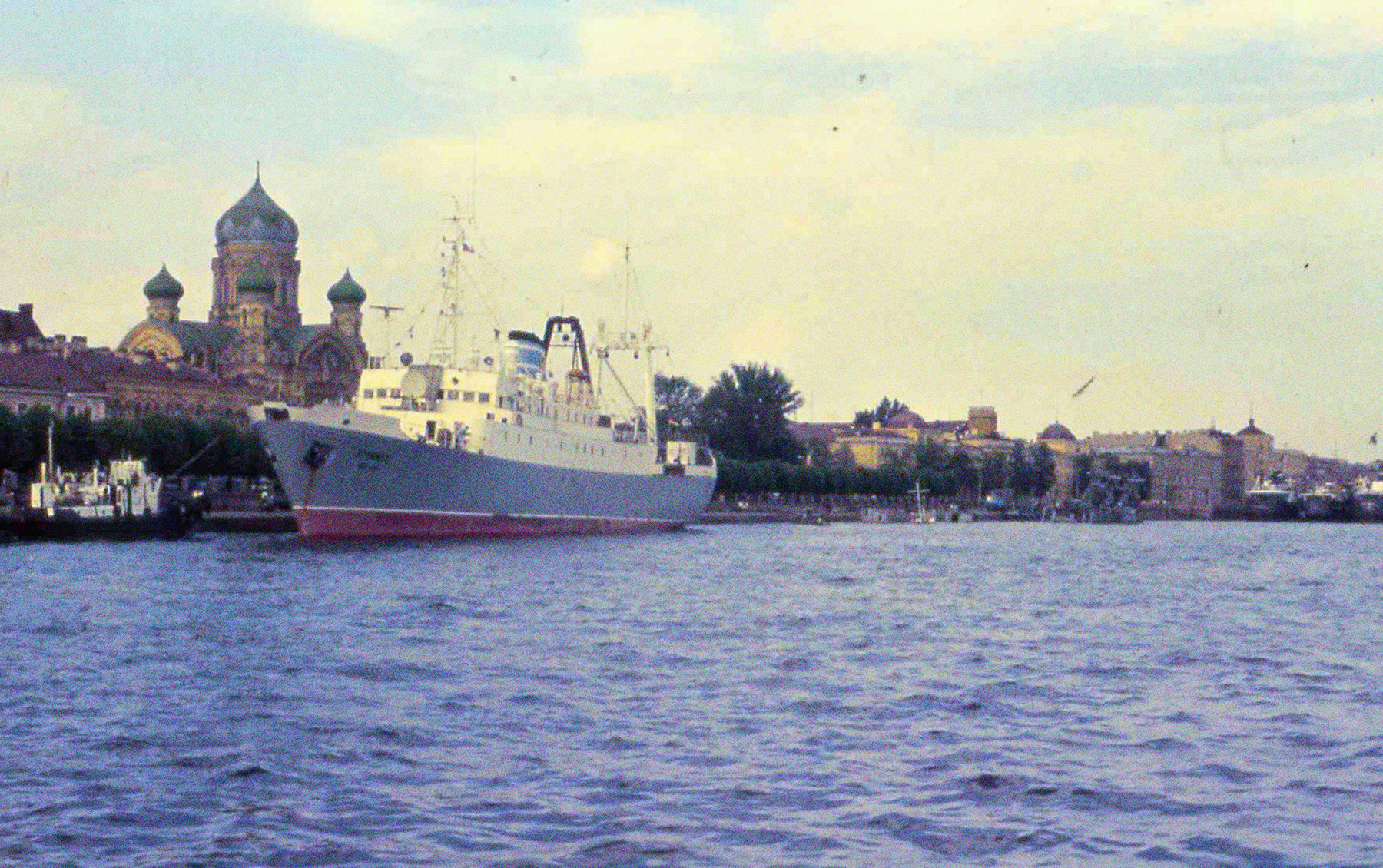 Die Stubnitz liegt im Hafen von St.Petersburg 1994. Im Hintergrund eine Promenade mit Bäumen und eine orthodoxe Kirche.