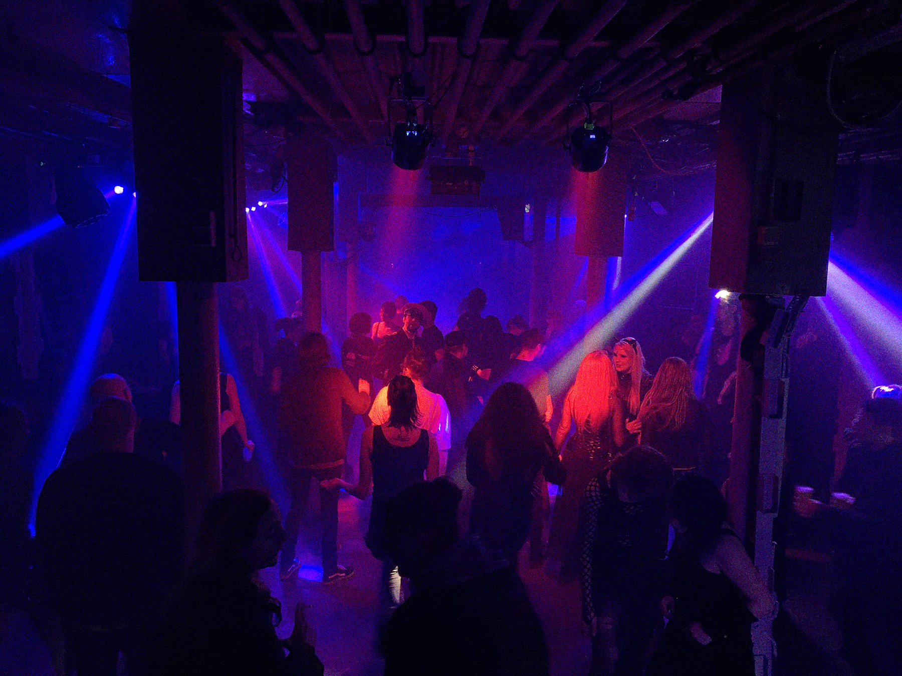 Eine Aftershow Party in Laderaum 1. Menschen tanzen in rotem und blauem Scheinwerferlicht. 